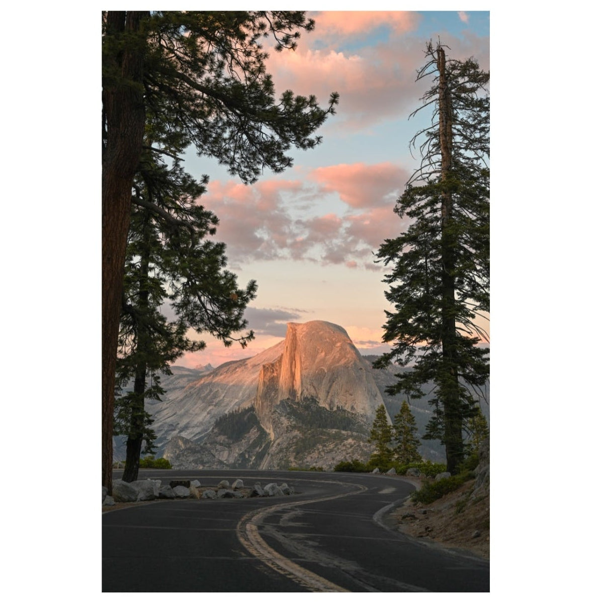Winding road leading to a mountain peak with trees on a clear sky background