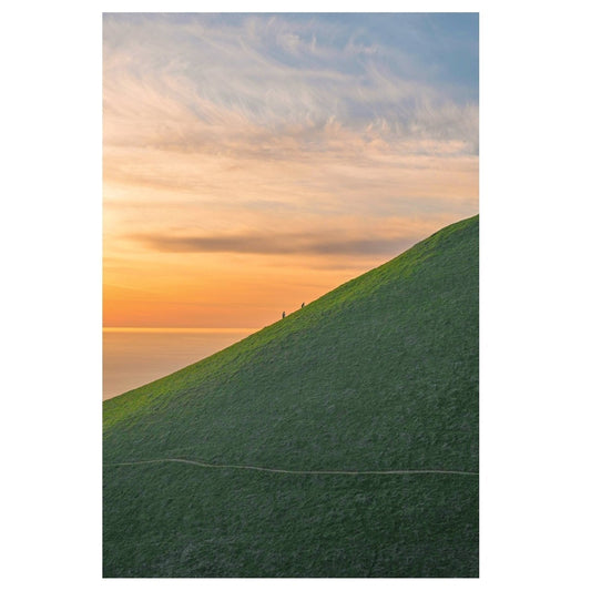 Sunny landscape with a green hill and colorful sky