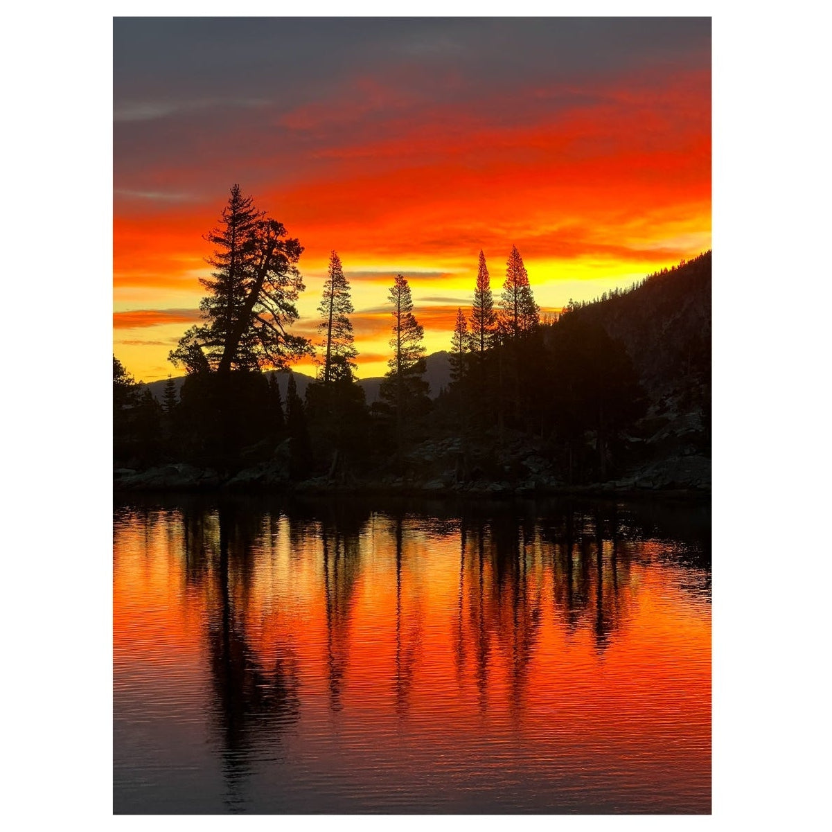Sunset over a lake with trees reflected in the water